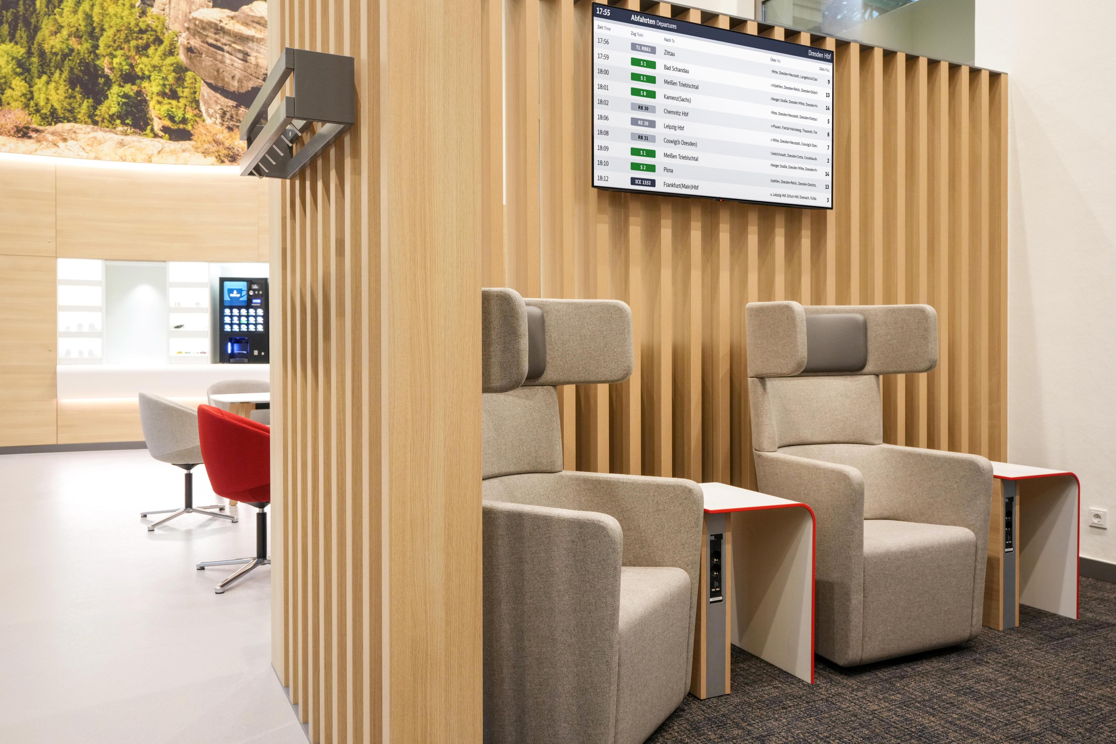 Grey wing chairs stand against a wooden wall that separates the relaxation area from the bistro area.