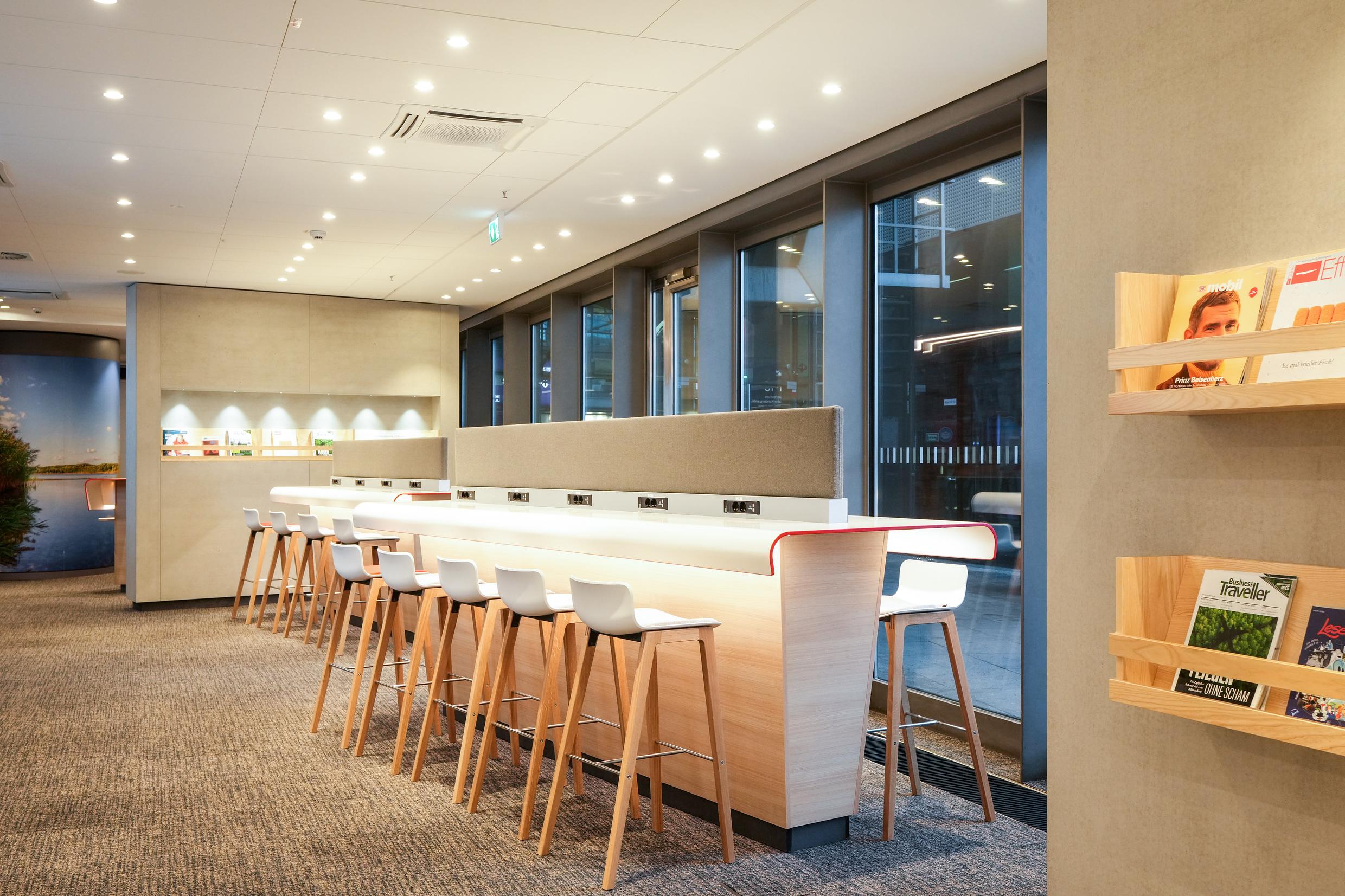 Hochtisch mit Hockern und Trennwänden in der DB Lounge Berlin Hauptbahnhof.