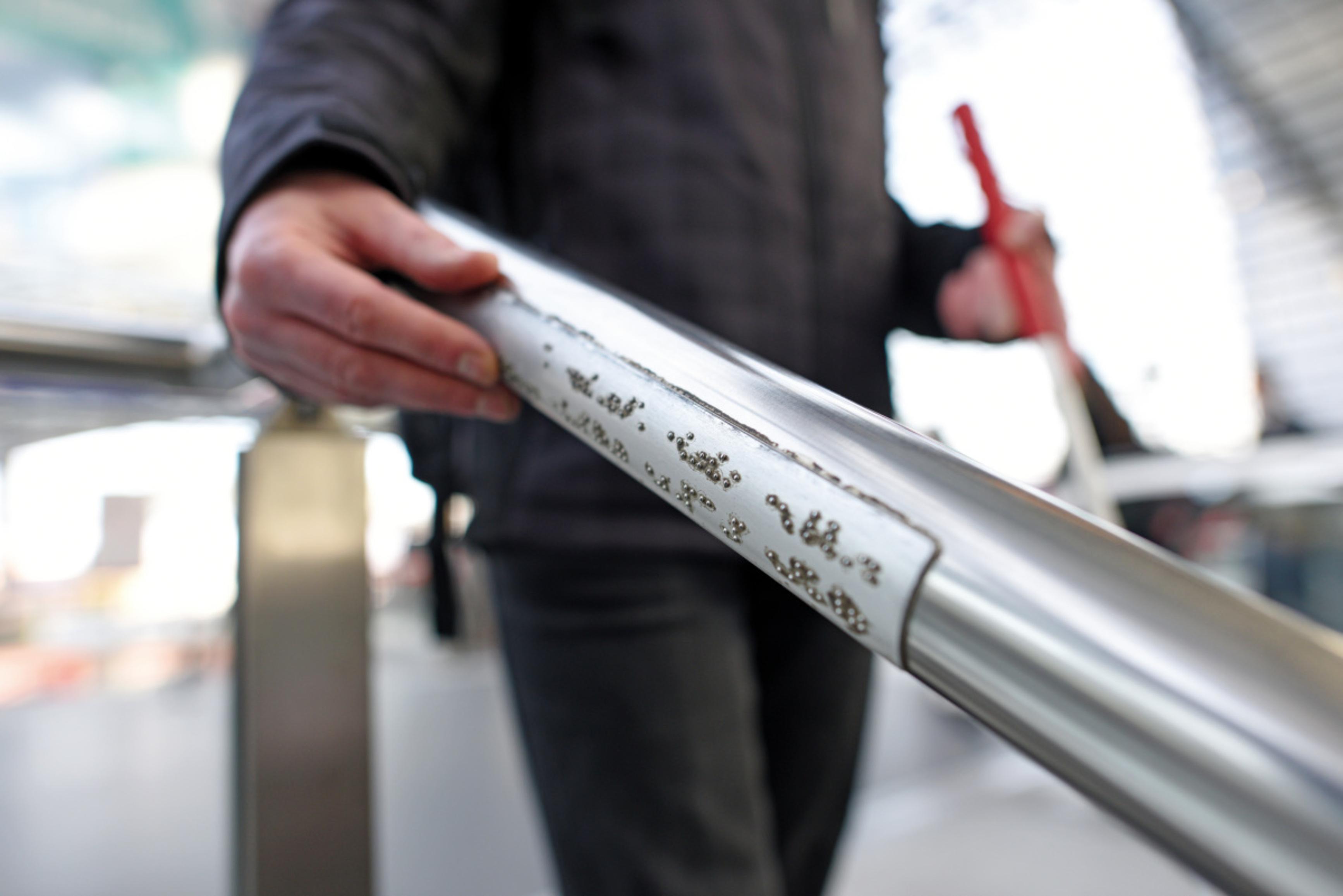 A tactile handrail sign on the railing of a staircase at the train station.