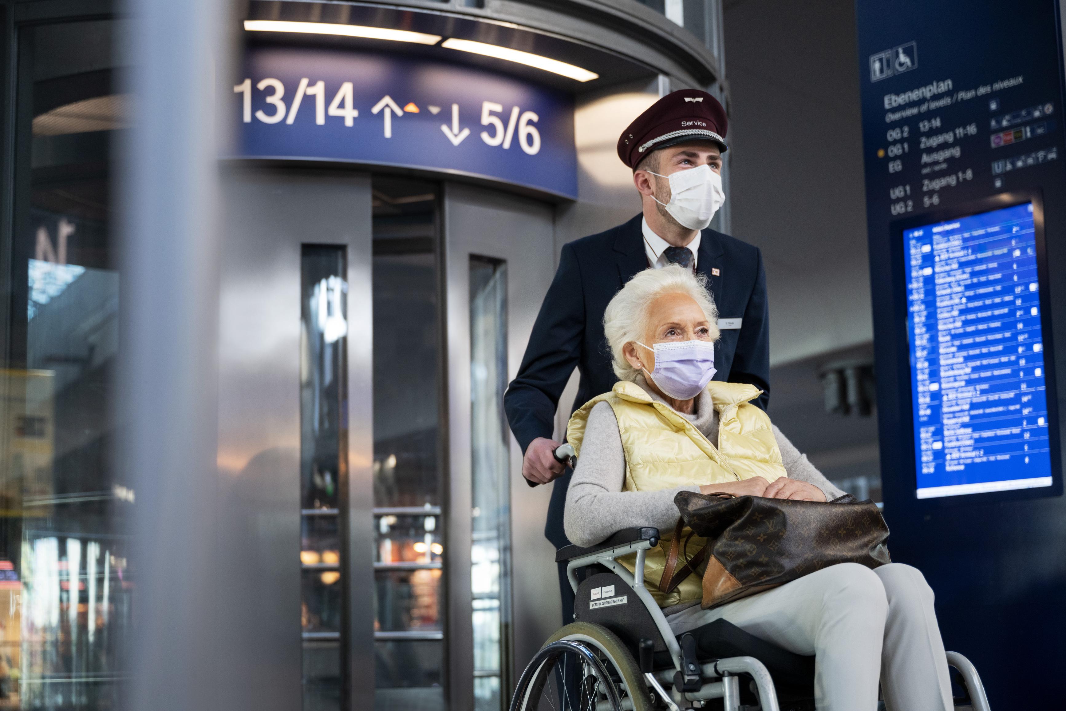 Ein Servicemitarbeiter schiebt eine Rollstuhlfahrerin im Hauptbahnhof Berlin.