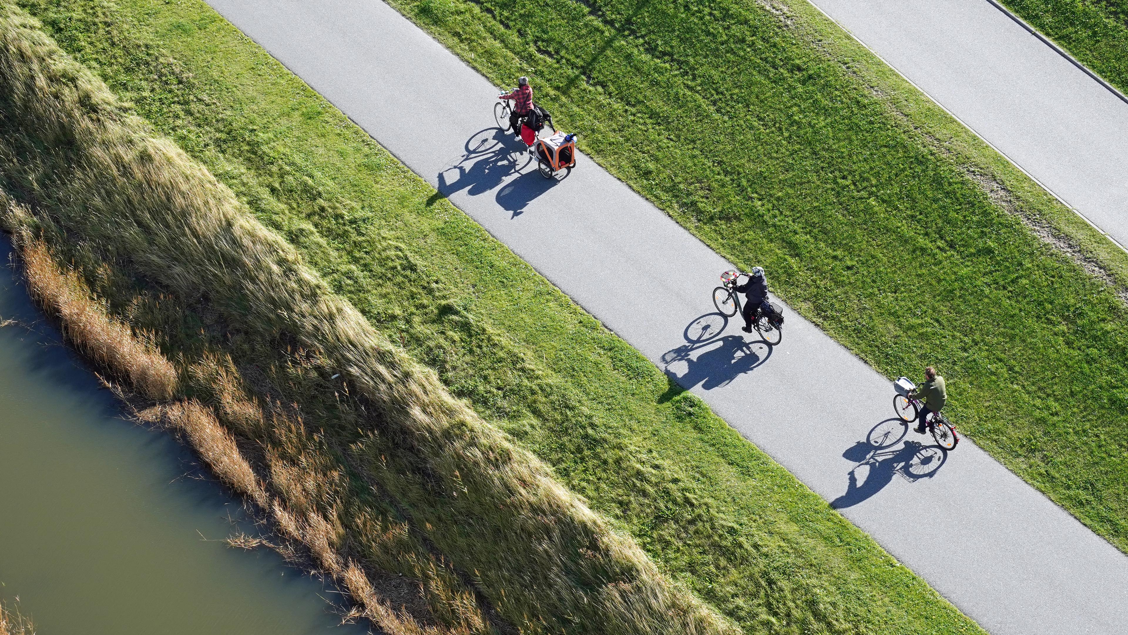 Ein Fahrradweg mit Fahrradfahrenden am Fluss.