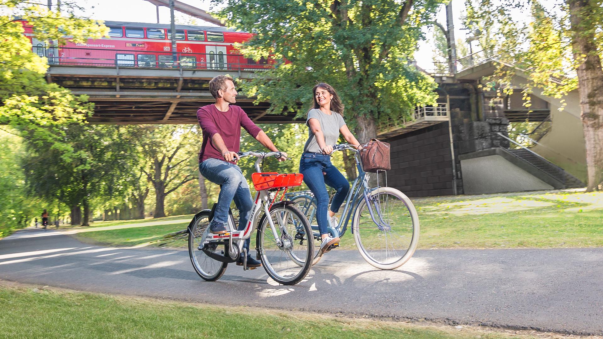 Zwei Fahrradfahrende auf einem Fahrradweg im Park.